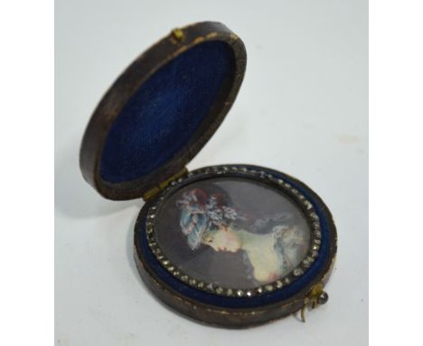 An 18th century circular portrait miniature of a young lady in a floral bonnet, in marcasite surround and morocco pocket-case