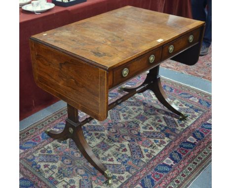 A Regency cross-banded sofa table, with rounded drop leaves to each end over a pair of frieze drawers opposing dummy drawer f