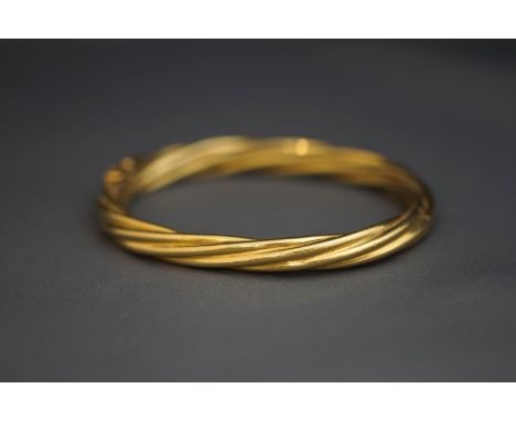 A yellow metal hinged bangle, of twist design, 17 g gross