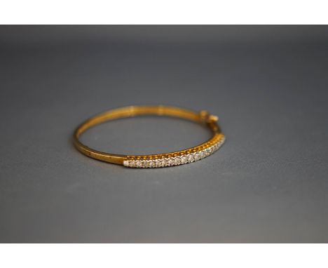 A 9 carat gold hinged diamond bangle, the twenty one graduated brilliant cuts totalling approximately 0.7 carats, internal di