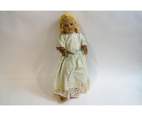 A 1940s/50s Chad Valley & Co fabric girl doll with painted facial features, wearing a yellow crochet cap, green cotton and la