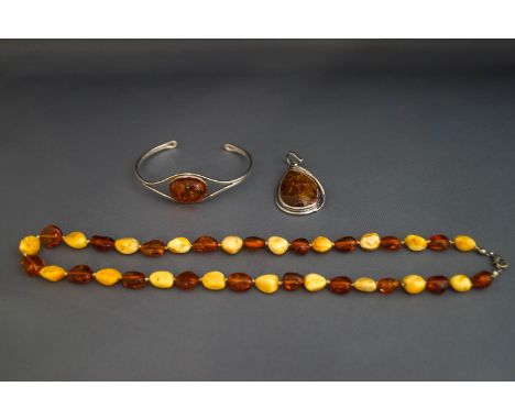 A modern silver &amp; amber torque bangle; a silver &amp; amber pendant; and an amber bead necklace