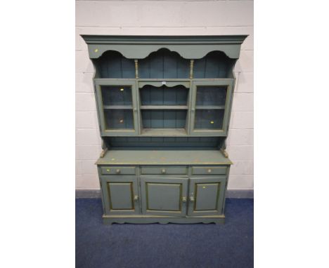 A GREEN PAINTED PINE DRESSER, the top with a fixed cornice, above a shelf with turned supports, glazed cupboard doors flankin