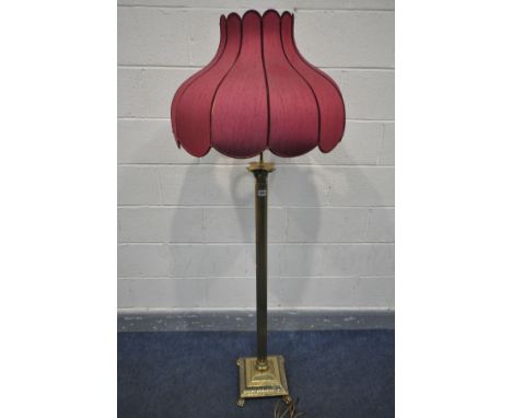 A BRASS CORINTHIAN COLUMN STANDARD LAMP, on claw feet, with a red tulip shaped shade, height to fitting 139cm