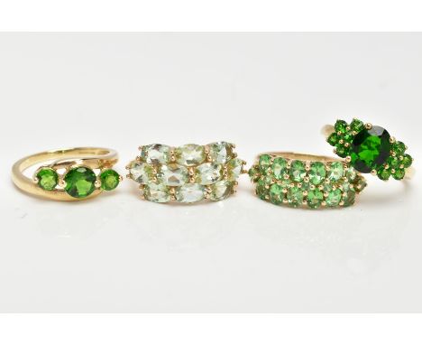 FOUR 9CT GOLD GEMSET RINGS, to include a three stone ring, assessed as circular cut diopside, prong set with a cross over des