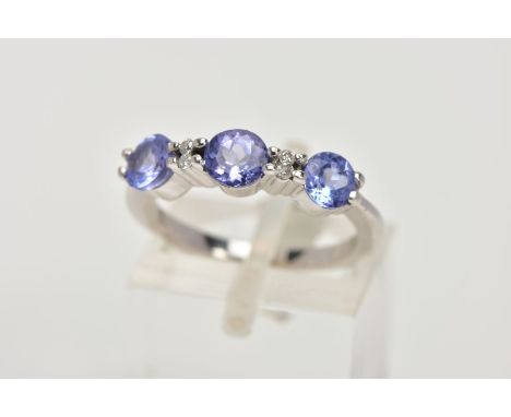 A TANZANITE AND DIAMOND RING, designed as three circular cut tanzanites each interspaced by two small brilliant cut diamonds,