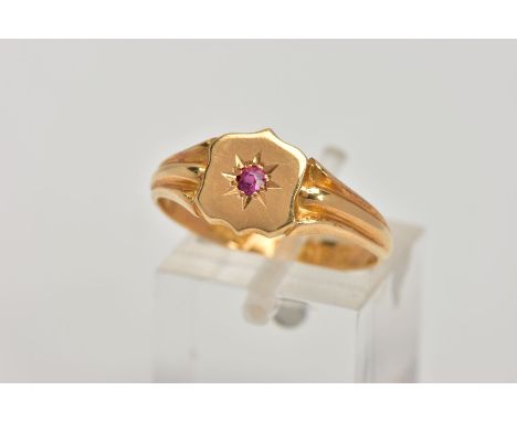 AN EARLY 20TH CENTURY 18CT GOLD SIGNET RING, in the form of a shield, with a star set circular cut ruby to the centre, textur