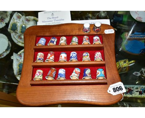 TWENTY ROYAL WORCESTER PORCELAIN THIMBLES, together with a wooden wall display shelf and Royal Worcester thimble ephemera