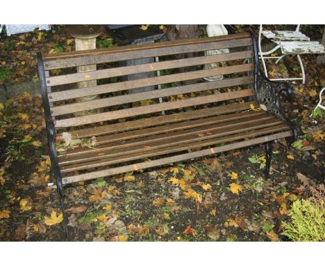 A WOODEN SLATTED GARDEN BENCH with cast iron bench ends, width 127cm x depth 60cm x 74cm