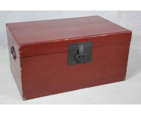 A Chinese red lacquered hardwood travelling trunk with twin metal carrying handles and lock. H.37 W.73 D.45cm 