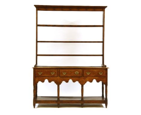 A George III oak dresser, the plate rack back over shaped apron on ring turned supports, three drawers, united by a pot board