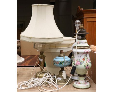 A floral painted opaline glass oil lamp, converted to electricity, another painted glass table lamp and two further oil lamps