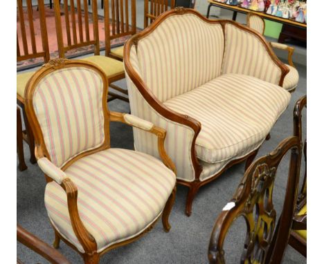 A French carved two seat sofa; and a pair of open armchairs to match, in striped upholstery (3) 