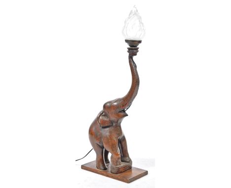 A retro mid century hardwood African elephant table lamp with Olympic flame glass shade. The elephant with raised trunk havin