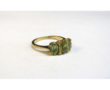 A 9ct gold three stone peridot ring. Size K/L, 2.6g 