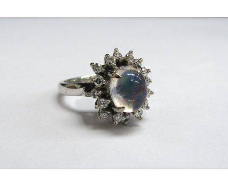 A white gold ring with oval cabochon moonstone framed by diamonds, stamped 14k. Size M/N, 5.8g 