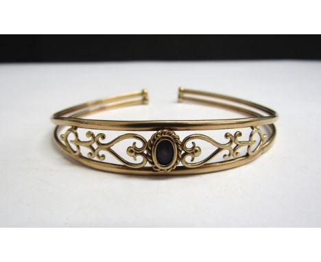 A 9ct gold open bangle with a single opal set in heart and scroll design, 5g 