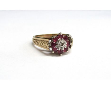 A 9ct gold ruby and diamond daisy ring with textured shoulders. Size O/P, 3.9g 