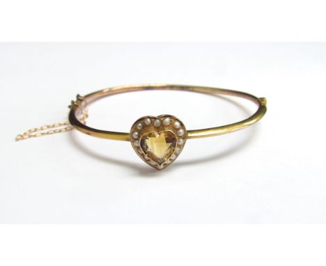 A gold hinged bangle with a central heart shaped citrine framed by seed pearls, unmarked, 5.5cm x 5cm, 4.3g 