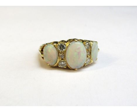 An 18ct gold ring set with three oval opals spaced by three old cut diamonds, pierced scroll mount. Size M, 5.6g 