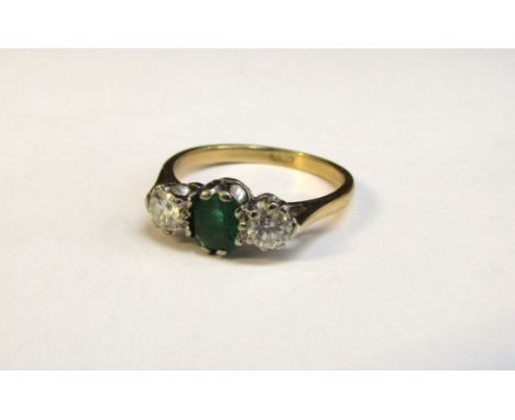 An emerald and diamond ring the centre emerald 5mm x 4mm flanked by 0.25ct approx diamonds, stamped 18ct. Size  O, 3.3g 