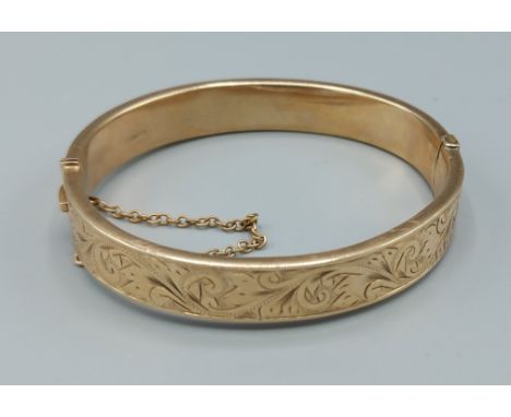 A 9ct gold bangle with engraved decoration, 6.5cms by 5cms, 16.8gms 
