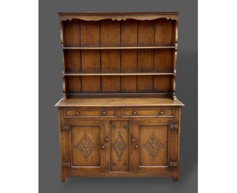 An oak dresser, the borded shelf back above two drawers and two cupboard doors flanked by stiles, 137cms wide, 47cms deep and