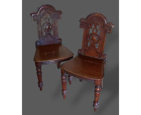 A pair of Victorian hall chairs, each with a shaped pierced back above a panel seat raised upon turned legs 