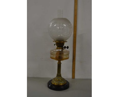 An oil lamp with frosted glass shade, clear font and brass base