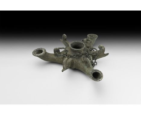 1st century AD. A bronze hanging oil lamp comprising a central bowl and three radiating nozzles each with a flared rim and pi