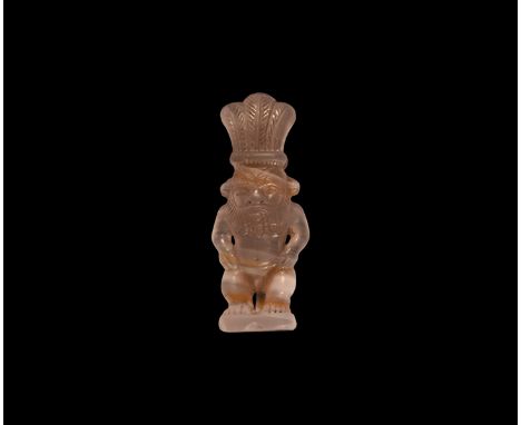 New Kingdom, 1550-1070 BC. A carved agate figurine of Bes standing on a discoid base with hands on hips, wearing the three-fe