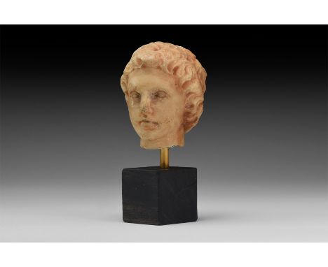 Ptolemaic, 3rd-1st century BC. A carved marble head of a youthful male with filet to the brow, thick tousled hair, wearing a 