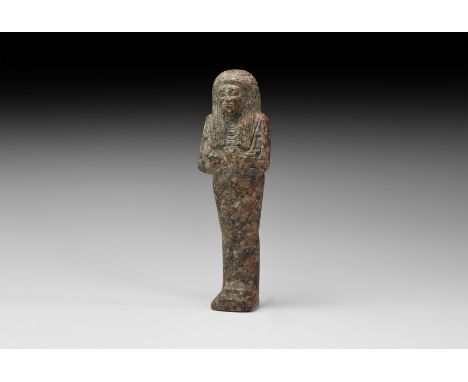 New Kingdom, 1550-1070 BC. A carved granite shabti with floral headdress on the tripartite wig, beaded collars, agricultural 