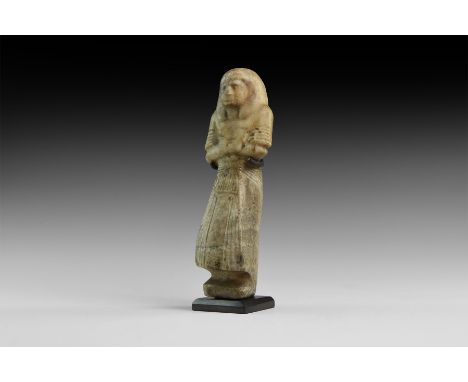 19th-20th Dynasty, 1305-1080 BC. A substantial alabaster shabti wearing civil dress, duplex wig, pleated robe with short slee