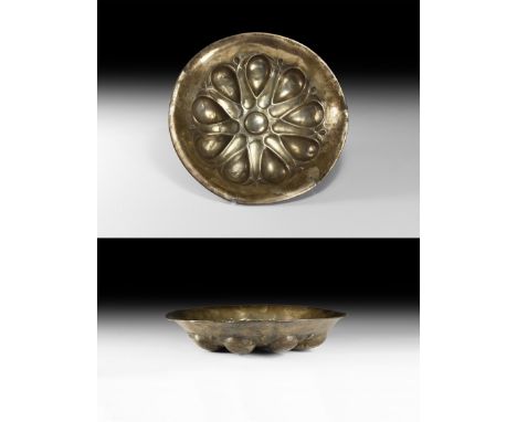 Early 1st millennium BC. A silver phiale with everted rim, radiating lotus-flower details and central mesomphalos boss. See G