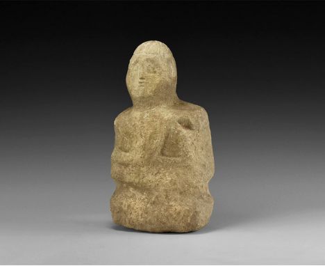 2nd century BC-1st century AD. A carved limestone statue of a figure with segmented cap, deep shoulders, braided hair to the 