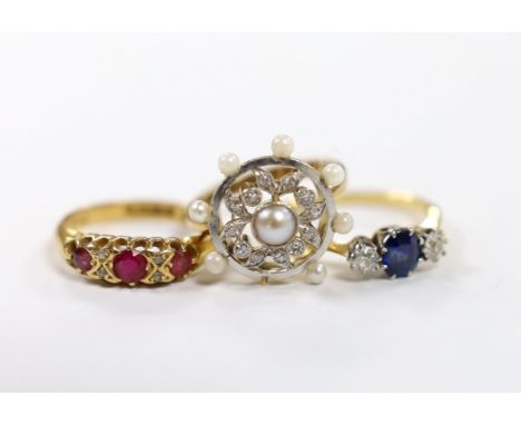 An 18ct, sapphire and diamond set three stone ring, a George V 18ct gold and three red stone set ring with diamond chip space