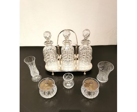 A silver plate tantalus with a swing handle and three cut glass decanters, a pair of silver plate and cut glass jam jars, and