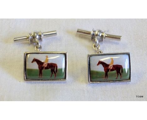 A pair of silver and enamel set cufflinks depicting a horse and rider