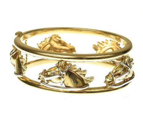 An 18k gold hinged bangleHermes style, with realistically modelled horse heads, in white and yellow gold, set between paralle