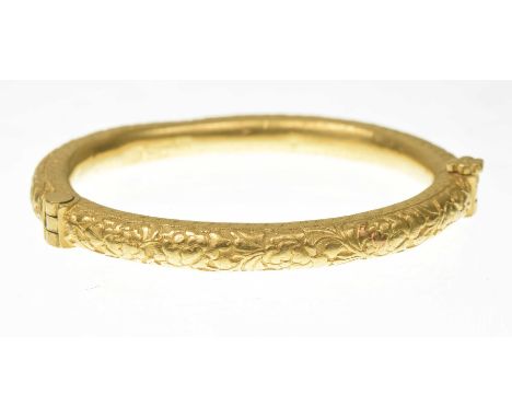 A Chinese gold hinged bangleProfusely engraved with foliate and scroll decoration, with a foliate screw fitting, bearing Chin