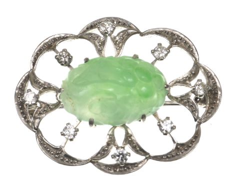 A jade and diamond broochThe central foliate carved jade, set to an open work precious white metal surrounds, with scalloped 