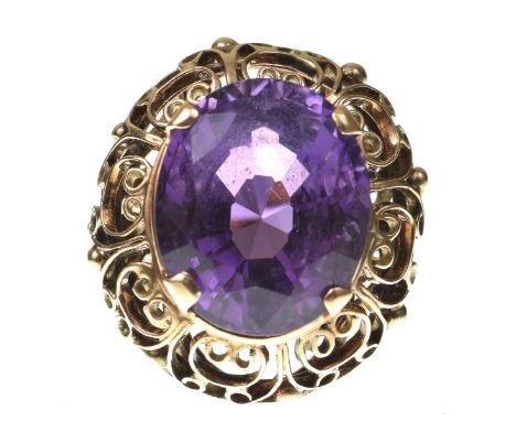 An amethyst dress ringThe oval shape amethyst, to an openwork scroll surround, in precious pink metal, ring size N