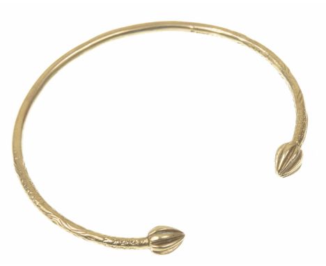 A torque bangleThe lozenge and scroll engraved bangle, terminating at each end with fluted drops, in 9k gold, length 7.8cm, w
