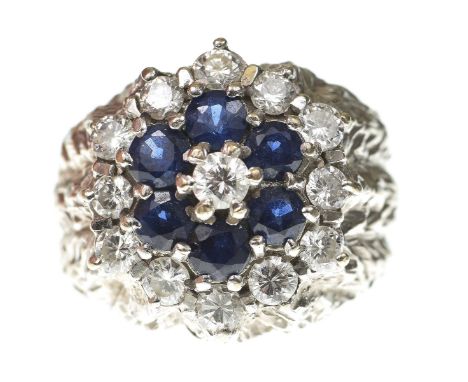 A sapphire and diamond cluster ring, circa 1970Centering a round brilliant-cut diamond, within a circular shape sapphire and 
