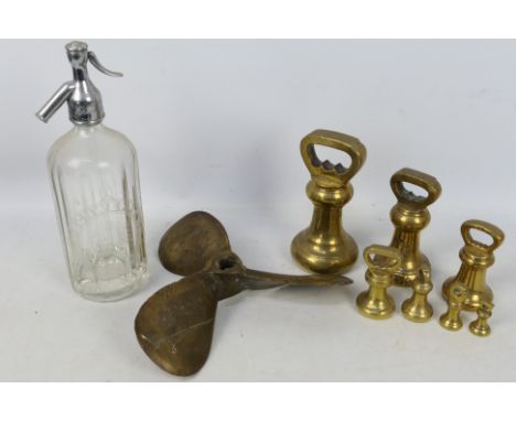 A brass propeller, brass weights and a vintage Schweppes soda syphon.