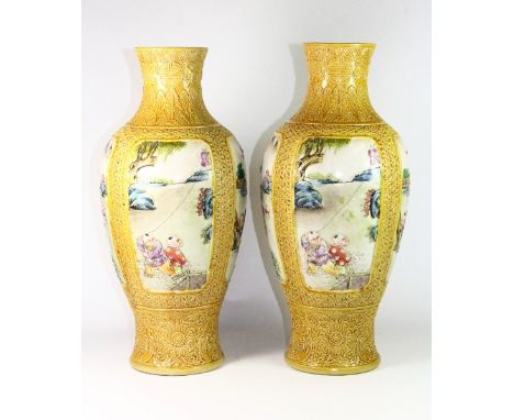 A pair of impressive Chinese relief decorated and hand enamelled porcelain vases with panels depicting children playing in a 