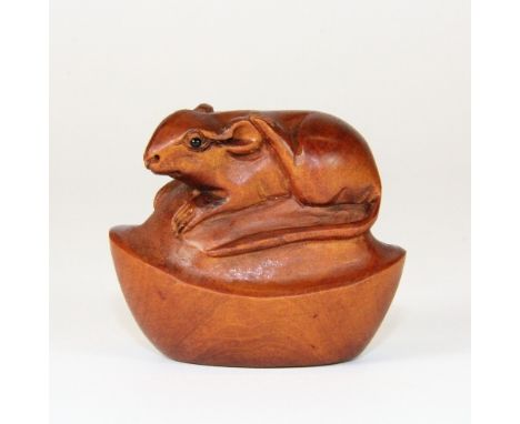 A carved and signed fruit wood netsuke of a mouse with black onyx eyes on a boat "cash"