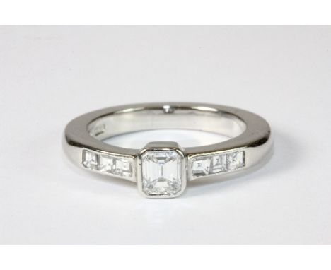 A heavy platinum ring set with a princess cut centre diamond and further princess cut diamonds to the shoulders .Size M