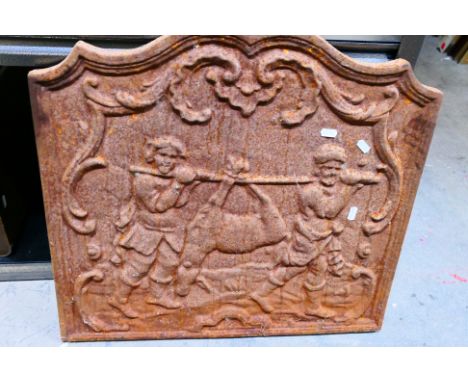 A vintage cast iron fireback depicting two men returning from hunting with their prey, approximately 55 cm x 60 cm. [W]